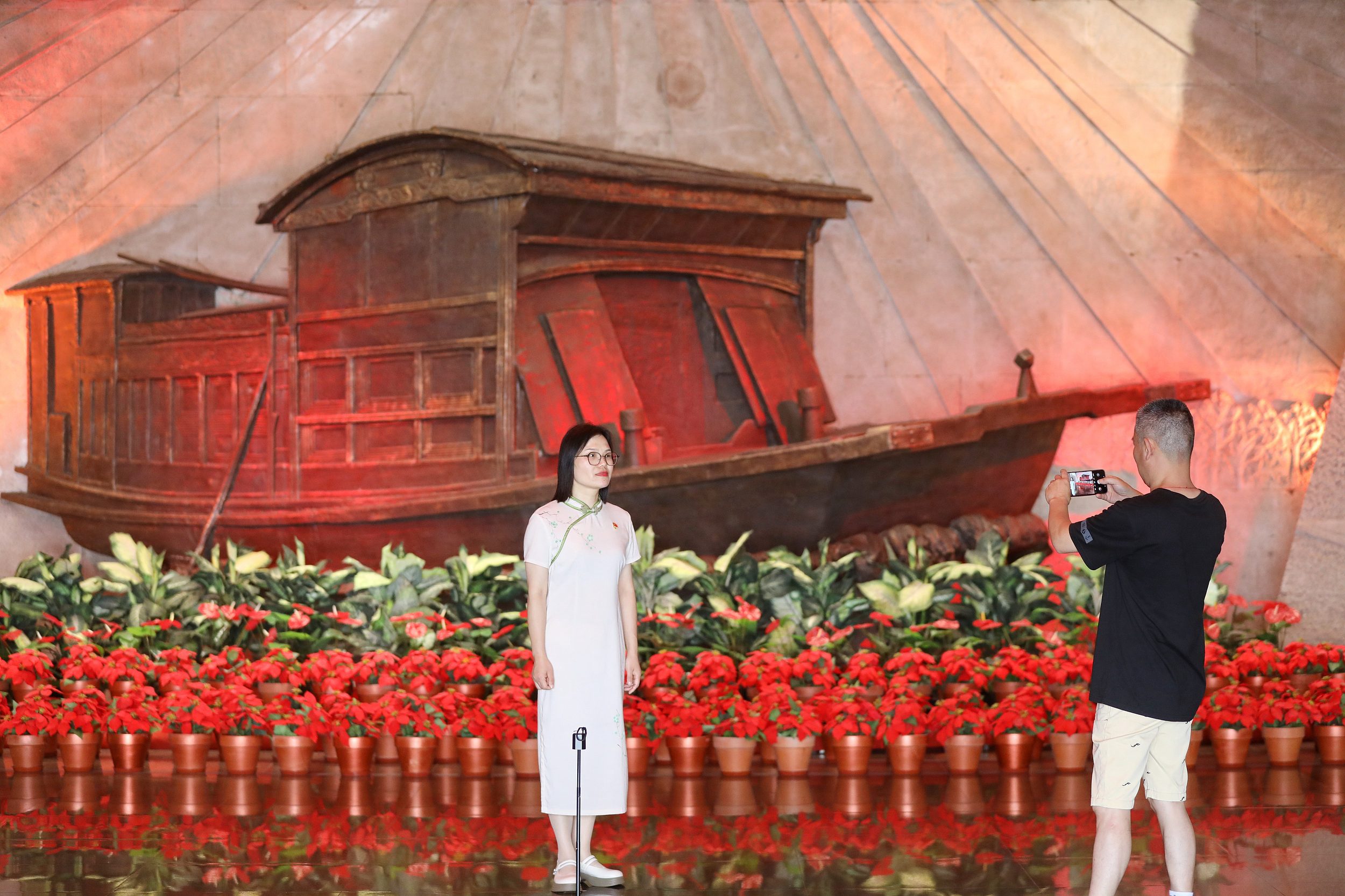 2025年6月24日，浙江嘉興，游客在南湖革命紀(jì)念館與紅船雕塑合影。（圖片來(lái)源：視覺中國(guó)）